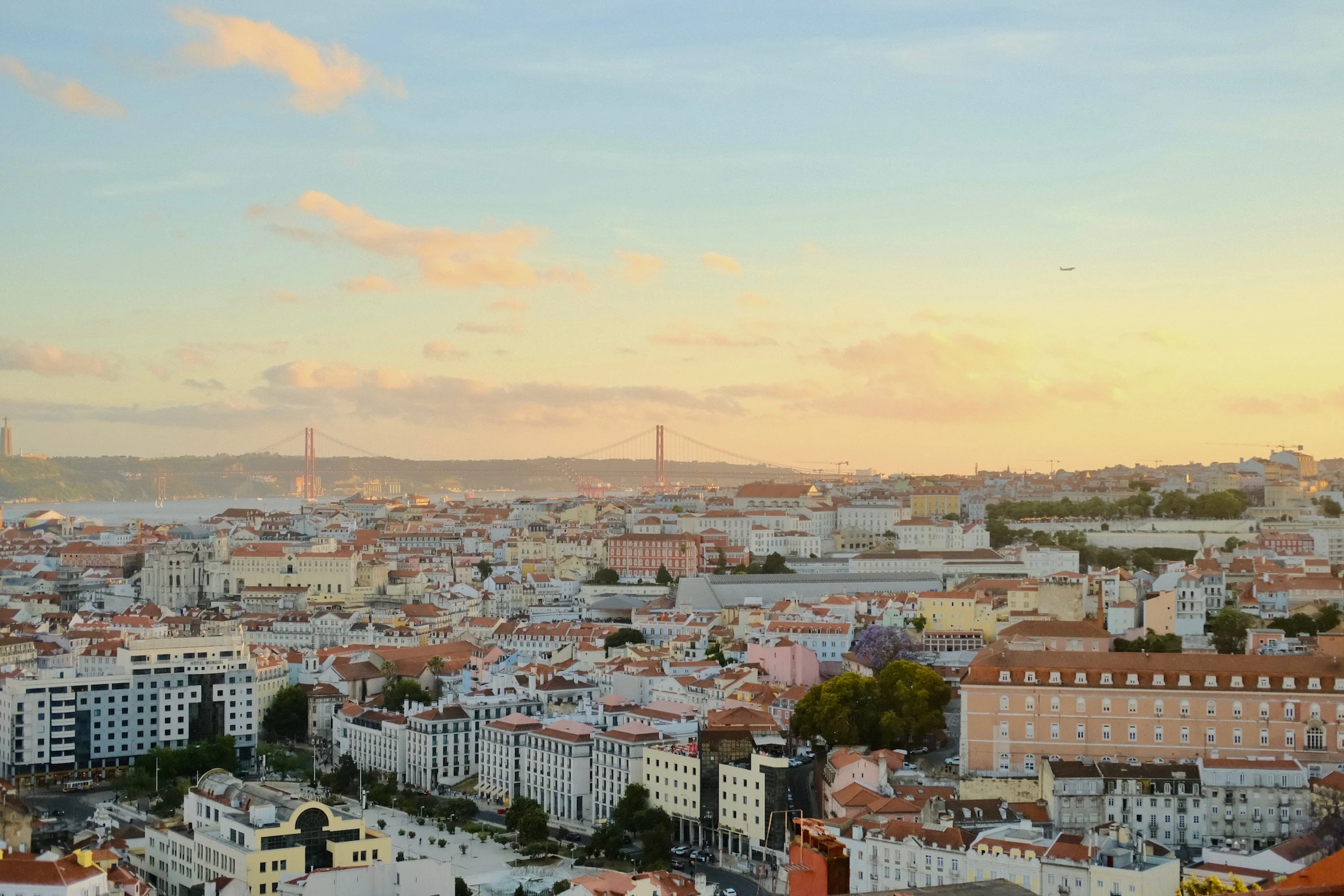 Lisbon rooftops stretching toward the river under a golden evening sky